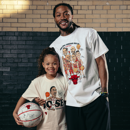 Young girl wearing t-shirts with sports-themed graphics, holding a basketball, against a brick wall.