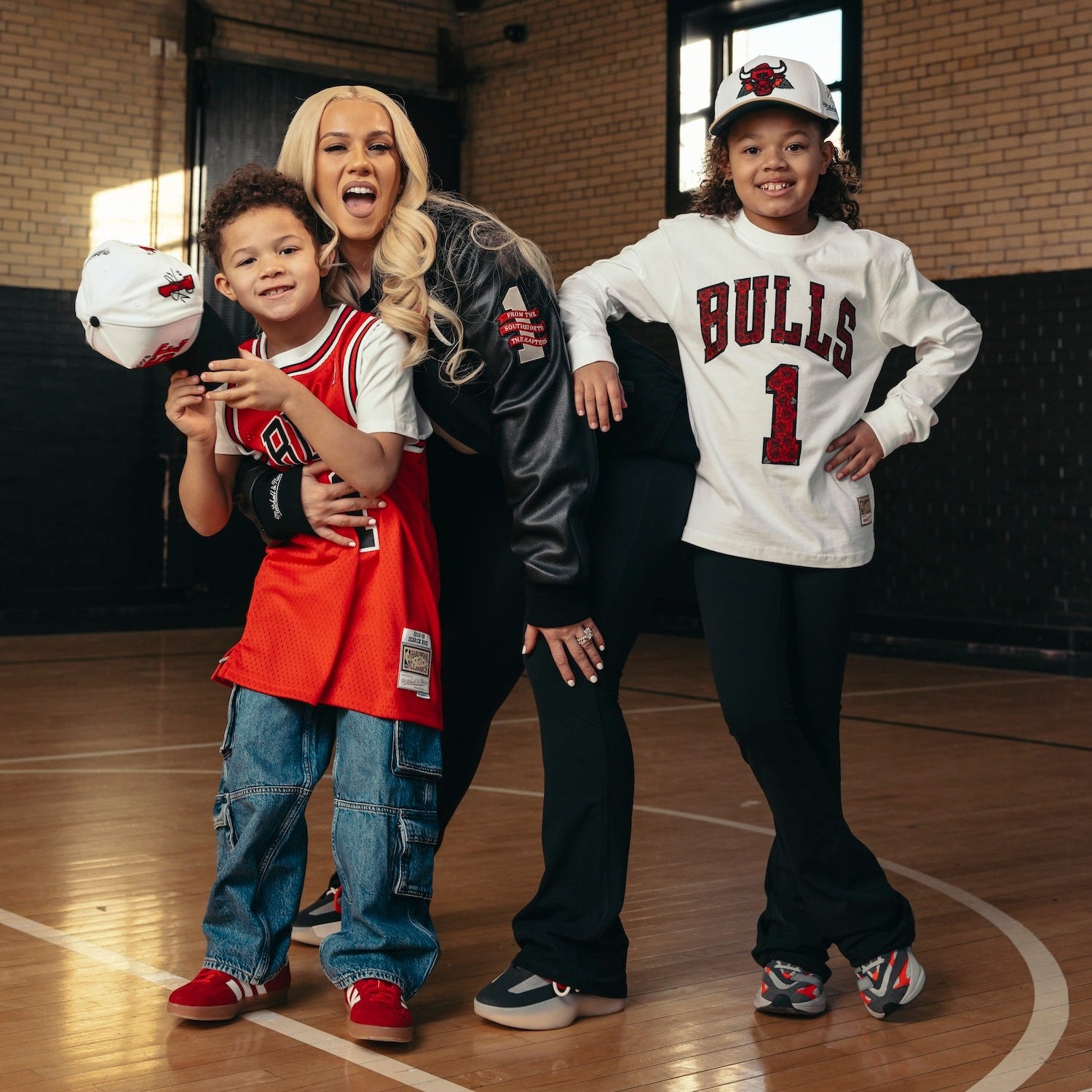 Woman and two children in sports-themed clothing on a basketball court