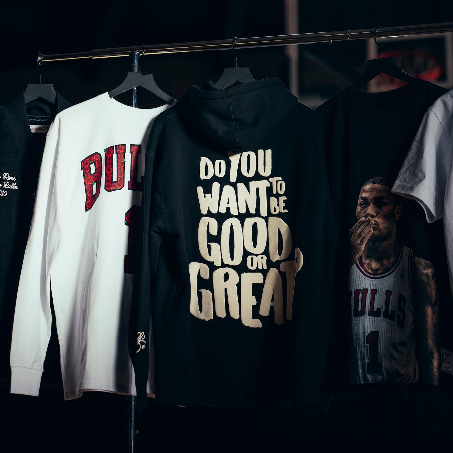 Black hoodie with motivational text on a rack with other shirts.