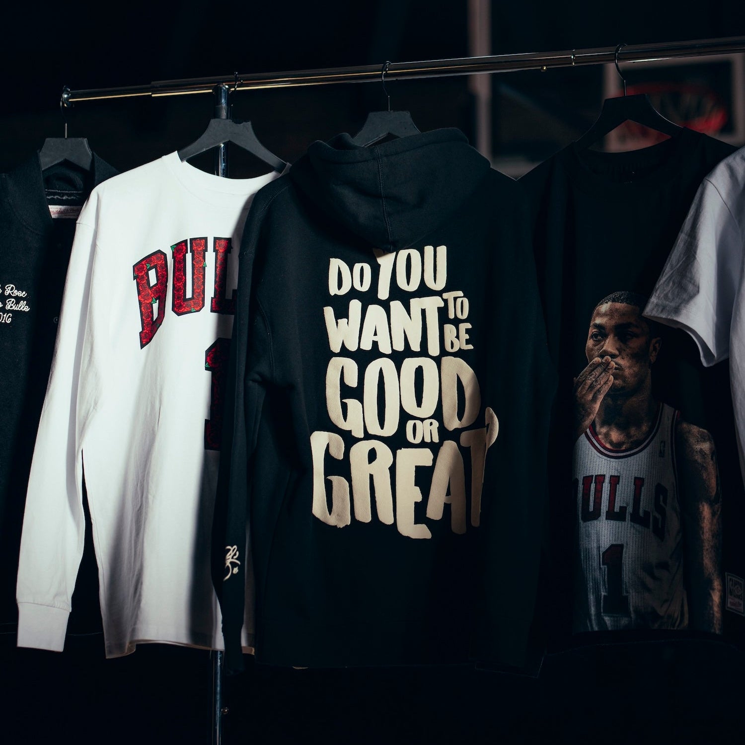 Black hoodie with motivational text on a rack with other shirts.